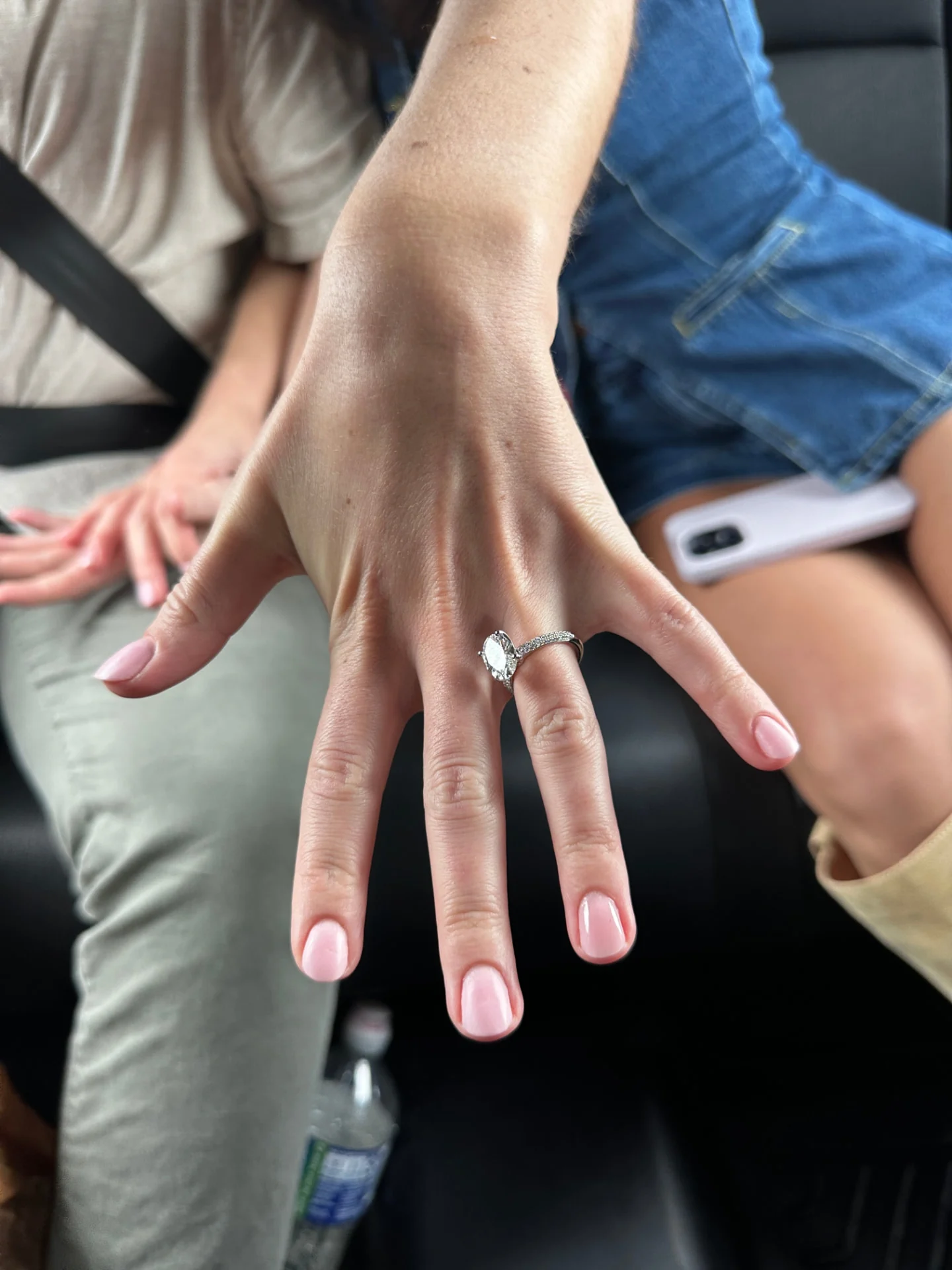 A hand showing an engagement ring inside a vehicle after an accepted proposal.